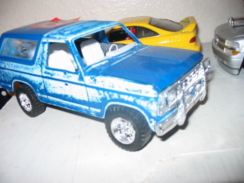 1986 Ford Bronco - A collection of toy vehicles are displayed on a flat surface.