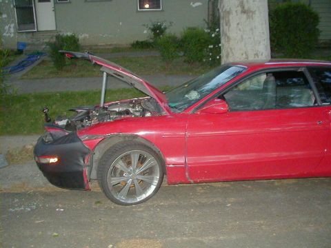 1993 Ford Probe - A red 1993 Ford Probe sits parked with its hood open, revealing the engine compartment and some front-end damage.