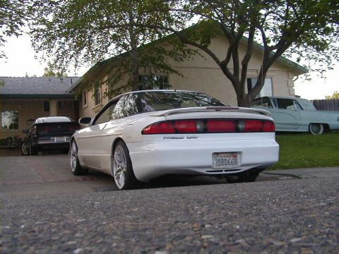1993 Ford Probe - A white 1993 Ford Probe is parked in a driveway next to another car and a house.