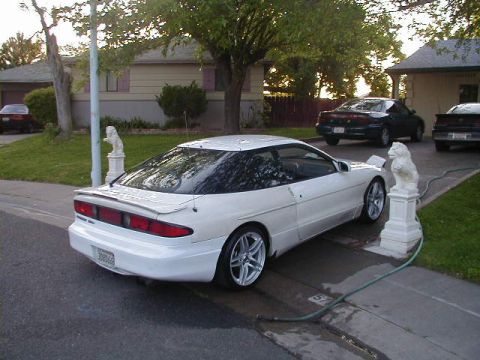1993 Ford Probe - A white 1993 Ford Probe is parked in a driveway, with two other vehicles visible in the background.