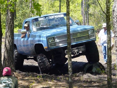 1989 Ford Bronco - This lifted pickup truck navigates rough terrain during an off-road event.