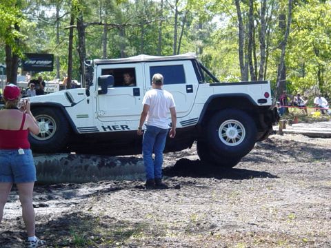 1989 Ford Bronco - White Hummer H1 navigates an off-road course with spectators in the background.
