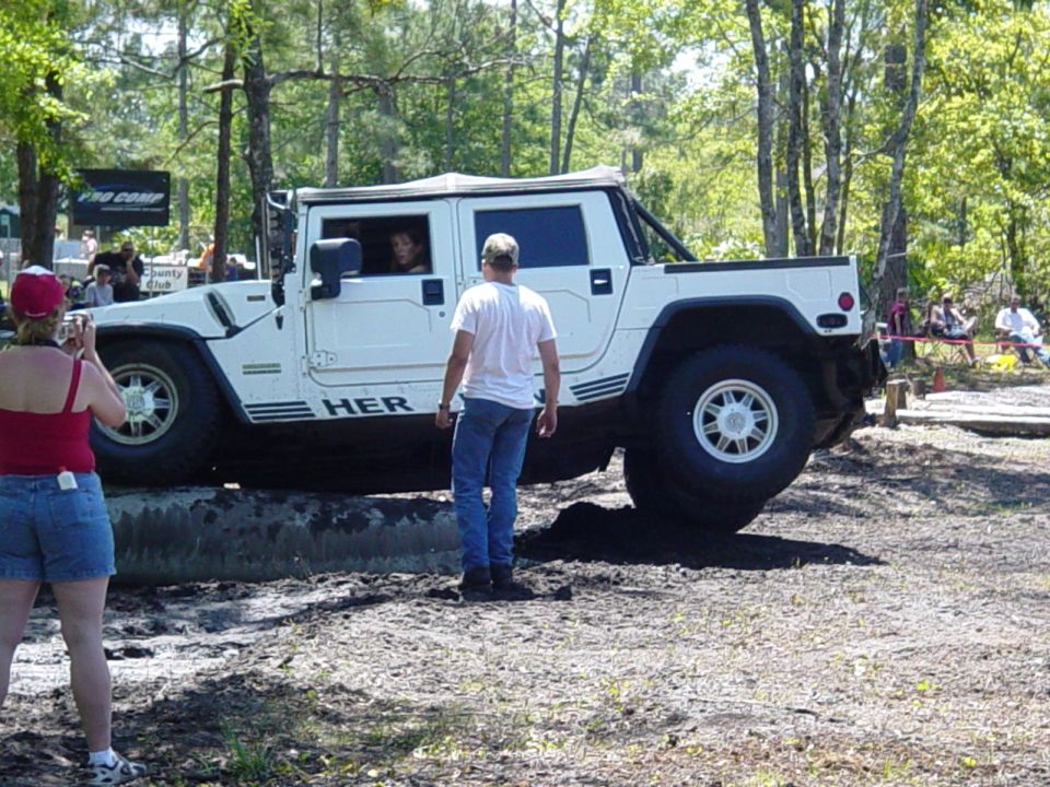 White Hummer H1 driving over an obstacle with people watching