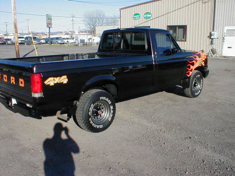 Black pickup truck with orange flame decals on the front fender and '4x4' graphics on the bed