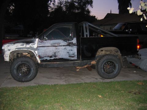 1991 Nissan Pathfinder - Side view of a modified 1991 Nissan Pathfinder pickup truck with a roll cage and off-road tires.