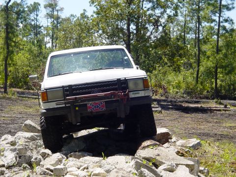 1989 Ford Bronco - White 1989 Ford Bronco tackling an off-road obstacle course with large rocks.