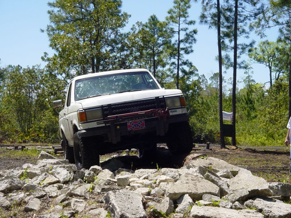 White 1989 Ford Bronco navigating a rocky obstacle course