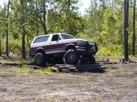 1989 Ford Bronco - A modified Ford Bronco navigates an obstacle course in a wooded area.