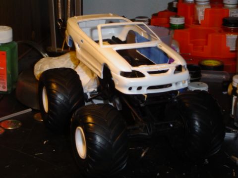 1979 Ford Bronco - Unfinished model monster truck with large tires sits on a workbench.