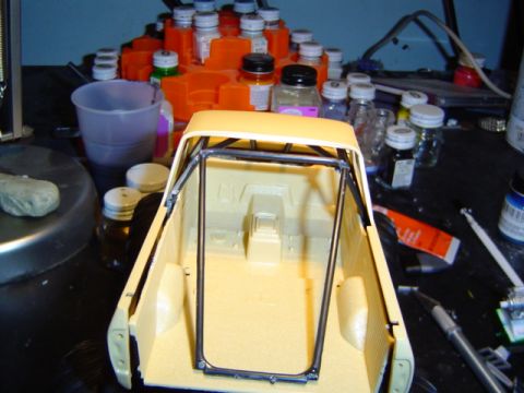 1979 Ford Bronco - Model car interior with roll cage assembly, surrounded by hobby paints and tools.
