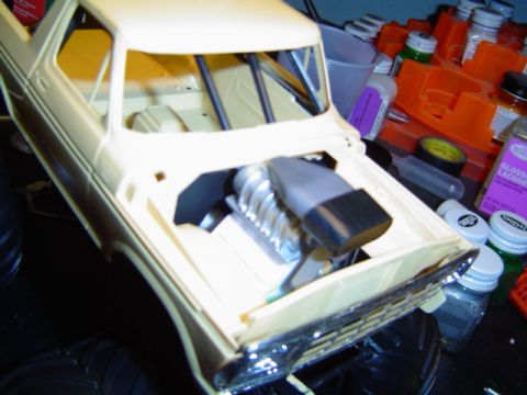 1979 Ford Bronco - Model car with a supercharger in the engine bay, next to hobby paints and tools.