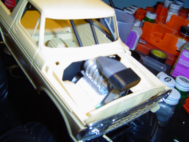 model car body with supercharger installed in engine bay, surrounded by hobby supplies