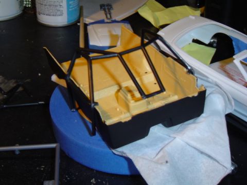 1979 Ford Bronco - A model car's interior and roll cage are being worked on, with another car body visible.
