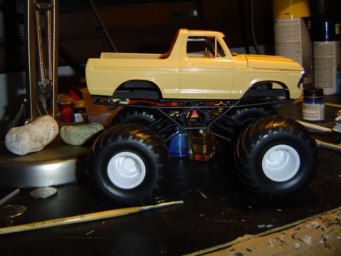 1979 Ford Bronco - A model truck with oversized tires sits on a workbench, surrounded by craft supplies.