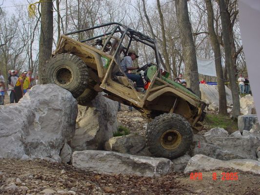 Modified off-road vehicle with a roll cage climbing over large rocks