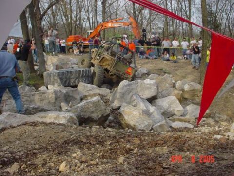 1992 Ford Bronco - An off-road vehicle tackles a challenging rocky terrain, with spectators and an excavator present.