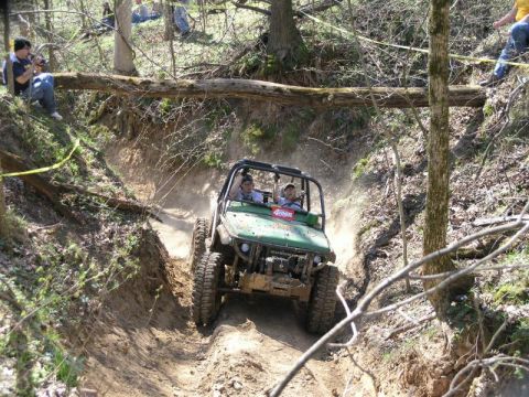 1992 Ford Bronco - An off-road vehicle navigates a challenging dirt path in a wooded area.