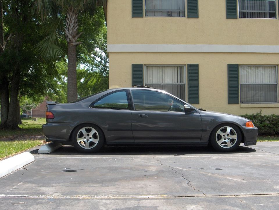Gray Honda Civic coupe, lowered, side view parked by tan building