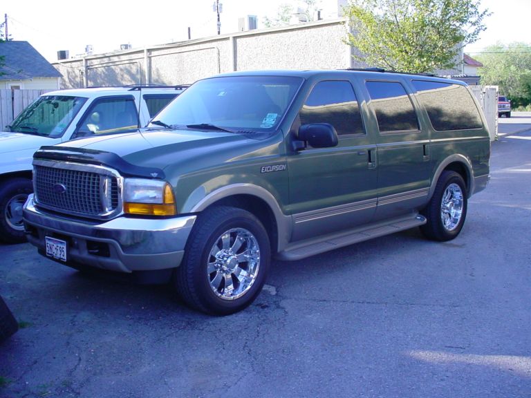 Green Ford Excursion SUV with tan lower trim and chrome wheels parked on asphalt, front three-quarter view