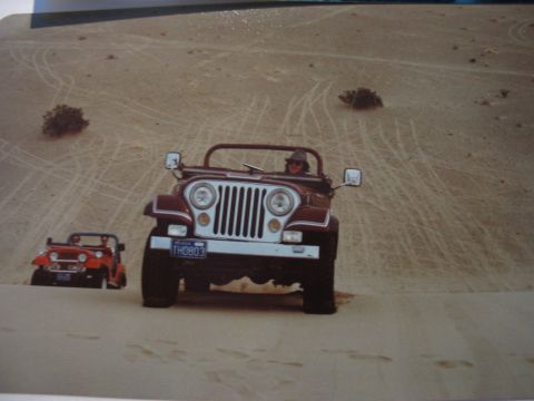 1995 Ford Bronco - Two Jeeps traverse sandy terrain, leaving tracks in the dunes.