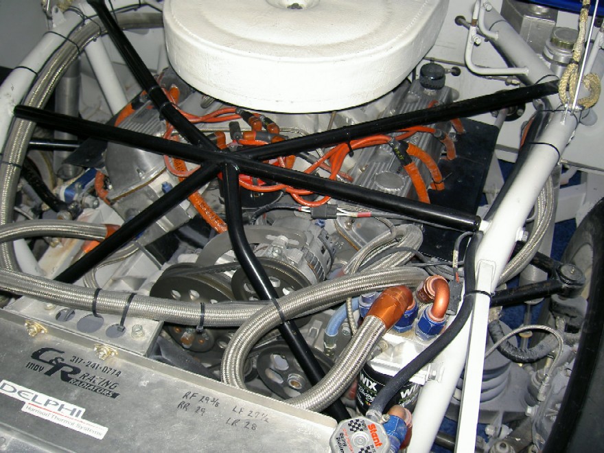Engine bay of a race car, showing V8 engine, roll cage, and braided hoses. Text includes 'DELPHI' and 'C&R RACING'