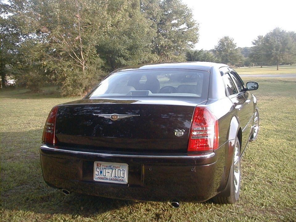 Rear view of a black Chrysler 300 sedan with North Carolina plate parked on grass