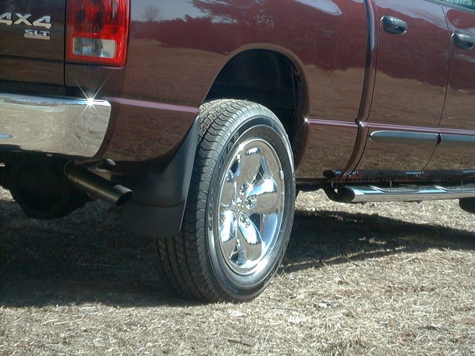 Rear side view of dark maroon 4x4 SLT pickup showing chrome wheel, mud flap, exhaust tip and step bar