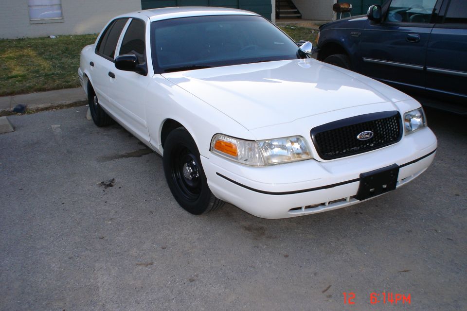 White 1998 Ford Crown Victoria with black steel wheels and a black grille, parked on asphalt