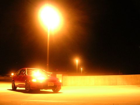1990 Volkswagen Corrado - A red hatchback is parked at night under a bright street light.