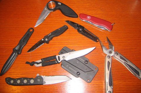 1978 Ford Bronco - Various knives and a multi-tool are displayed on a wooden table, with a website address visible at the bottom right.