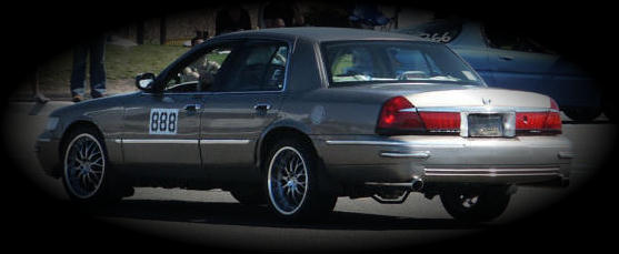 Silver Mercury Grand Marquis sedan, rear 3/4 view, '888' door number and chrome wheels
