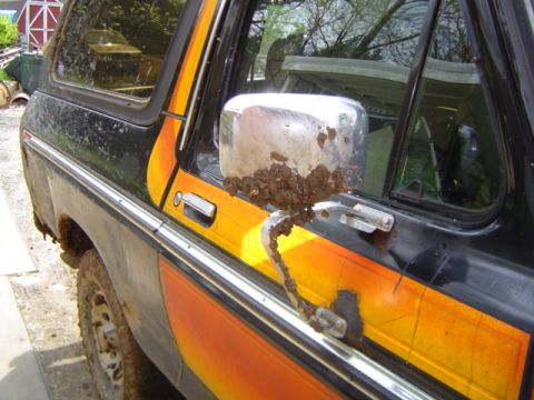 1979 Ford Bronco - Mud splatters the side mirror and body of this 1979 Ford Bronco, showing its off-road adventures.