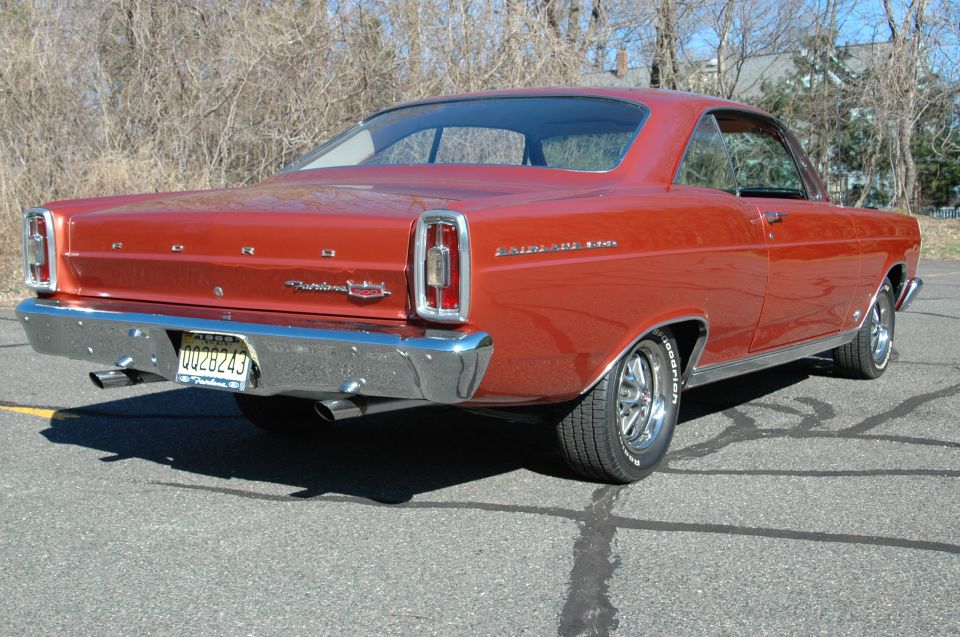 Red 1966 Ford Fairlane 500 coupe, rear 3/4 view, dual exhaust and mag wheels.