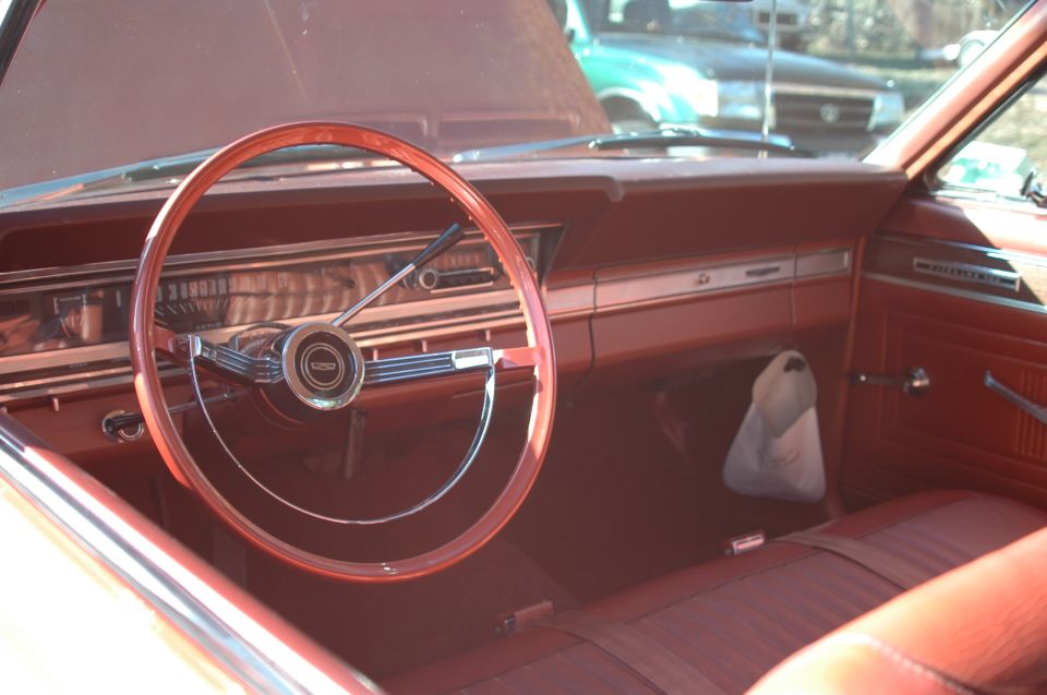 Vintage car interior with wood steering wheel and red vinyl seats and dash
