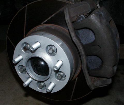 2001 Mercury Grand Marquis - Close-up view of a wheel spacer mounted on a vehicle's brake rotor and caliper assembly.