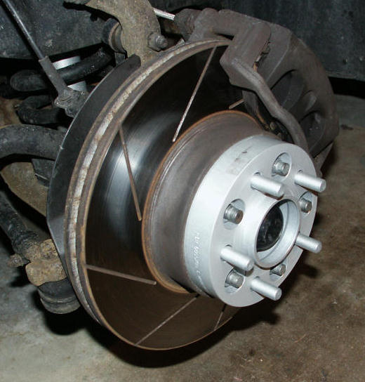 Close-up of a car's brake rotor, caliper, and wheel spacer assembly