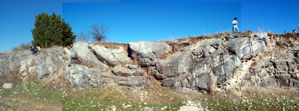 Rocky hillside with people and trees under a clear blue sky