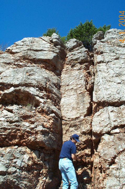 1996 Ford Bronco - A person in a blue shirt and jeans inspects a geological formation under a clear blue sky.