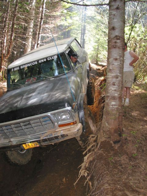 1978 Ford Bronco - A 1978 Ford Bronco navigates a challenging off-road trail, with a driver visible inside and a passenger standing nearby.