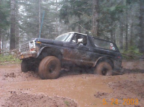 1978 Ford Bronco - This black 1978 Ford Bronco is deep in the mud, navigating a challenging off-road trail.
