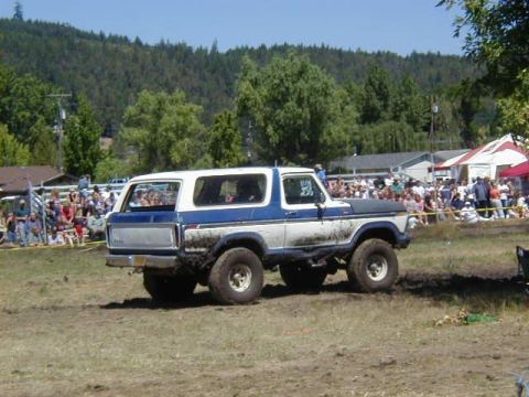 1978 Ford Bronco - A white and blue 1978 Ford Bronco navigates a muddy track in front of a crowd.