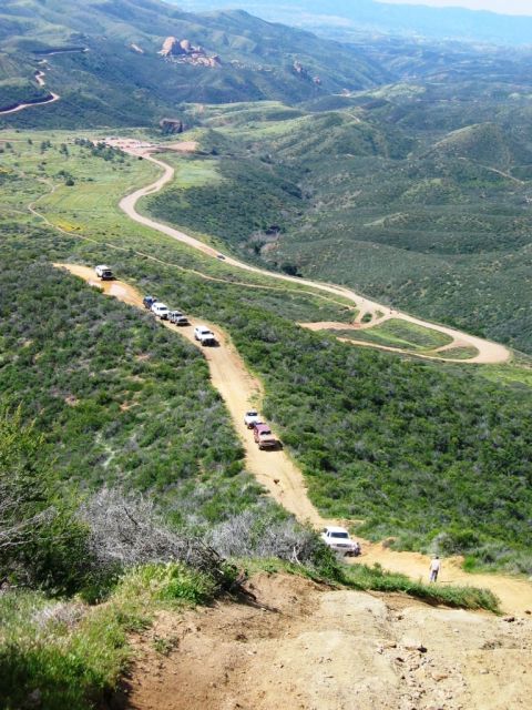 1988 Ford Bronco - A convoy of SUVs navigates a challenging dirt path in a scenic, mountainous region.