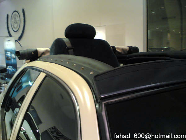 Car interior with black seats and a tan roofline, viewed from the rear passenger side