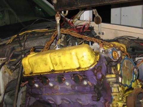 1985 Ford LTD Crown Victoria - An engine is suspended by a chain hoist, ready for installation or removal.