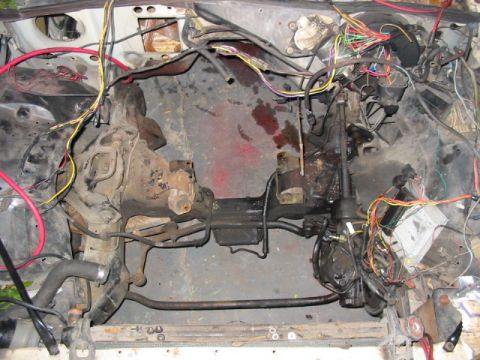 1985 Ford LTD Crown Victoria - The engine bay of a vehicle is shown with exposed wiring, transmission components, and a steering column, indicating a disassembled state.