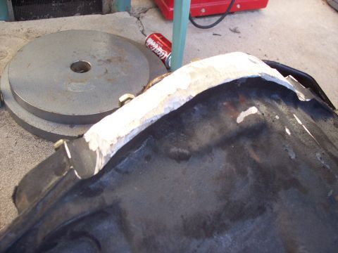 1988 Ford Bronco - A close-up view of a car part being worked on, with sealant applied to its edge.