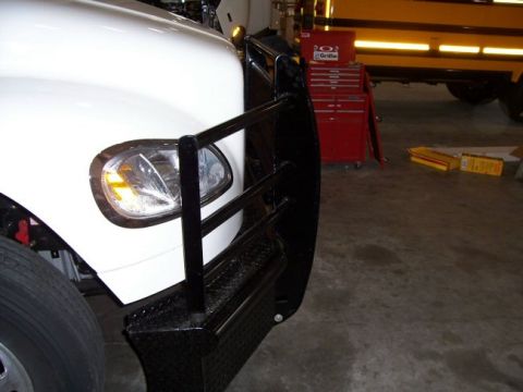 1978 Ford F-250 - A white truck's front corner is visible, a large black grille guard and a yellow turn signal light.
