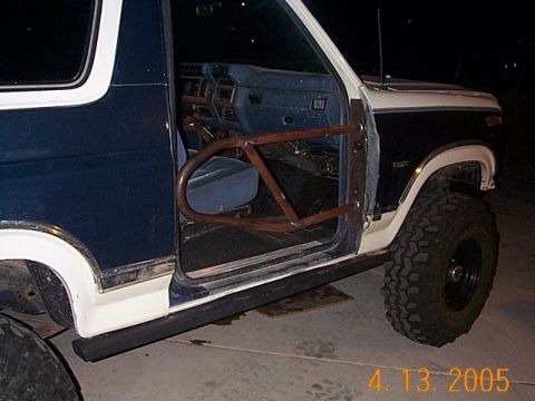 1986 Ford Bronco - A modified Ford Bronco, likely from the early 1980s, is shown with its driver's side door removed and replaced with a tube frame.