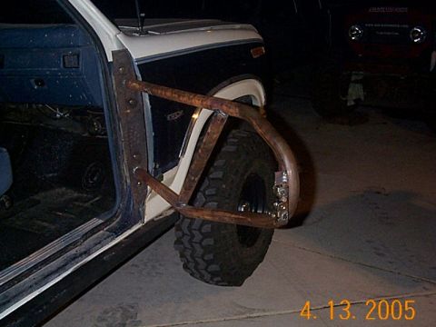 1986 Ford Bronco - This 1986 Ford Bronco features custom tube doors and aggressive off-road tires, with another vehicle visible in the background.