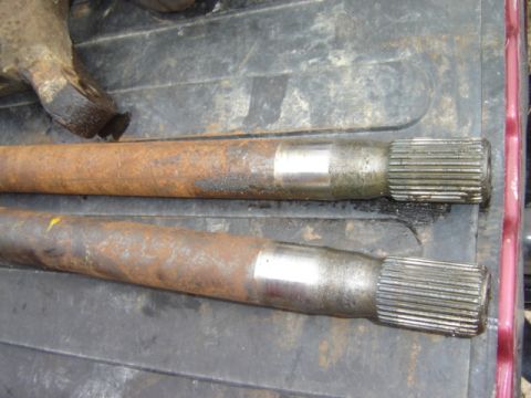 1992 Ford Bronco - Close-up of two rusty axle shafts, likely for a vehicle part replacement.